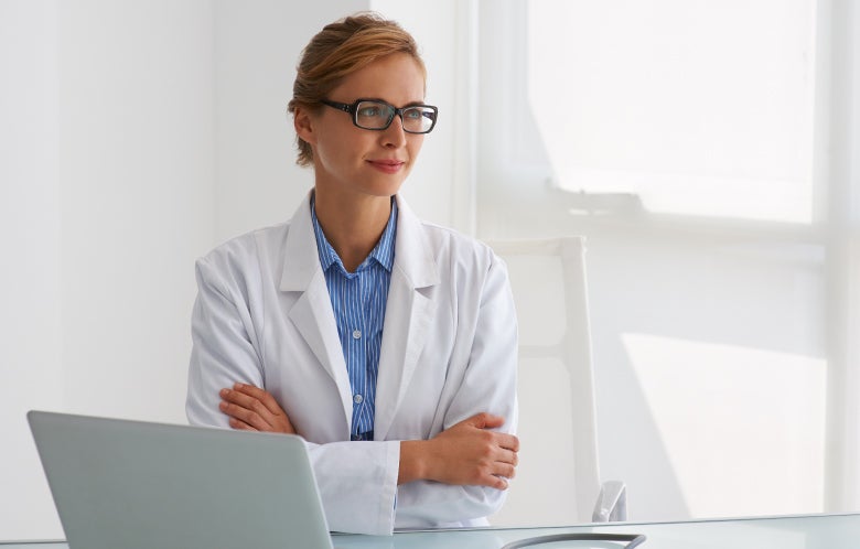 Doctor at desk with arms folded