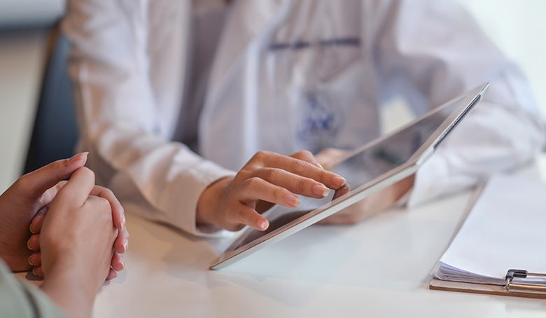 doctor showing a patient some information on a digital tablet