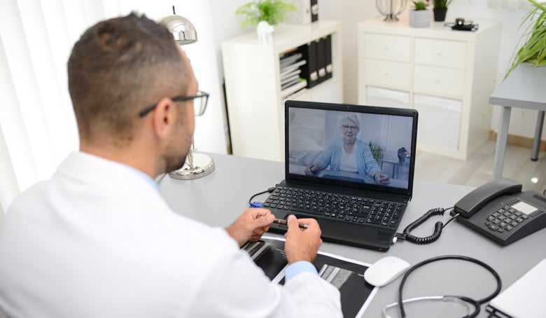 Male doctor on a telehealth call with an elderly woman.