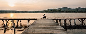 Person sitting on dock at dawn