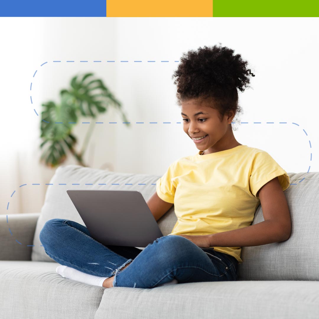 Girl in yellow shirt sitting on a couch using a laptop