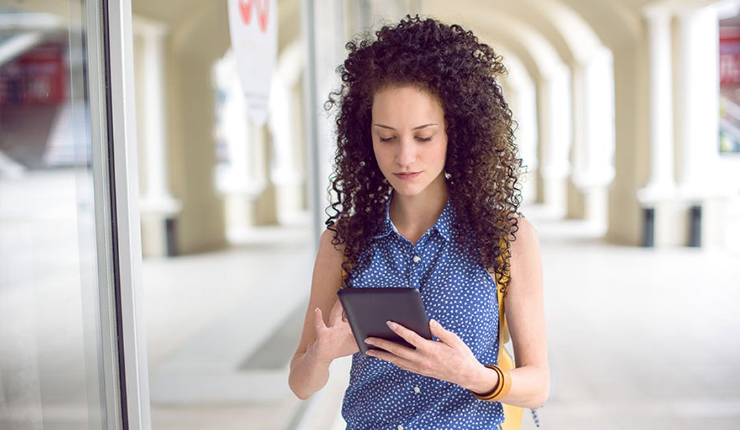 woman in a blue shirt scrolling on tablet
