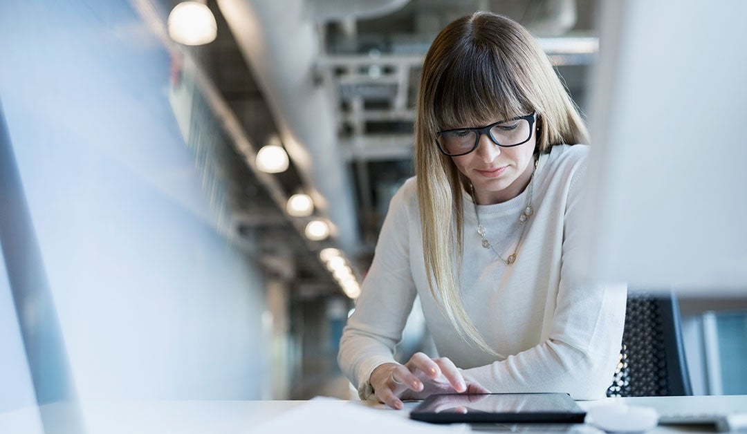 woman at a desk scrolling on a tablet