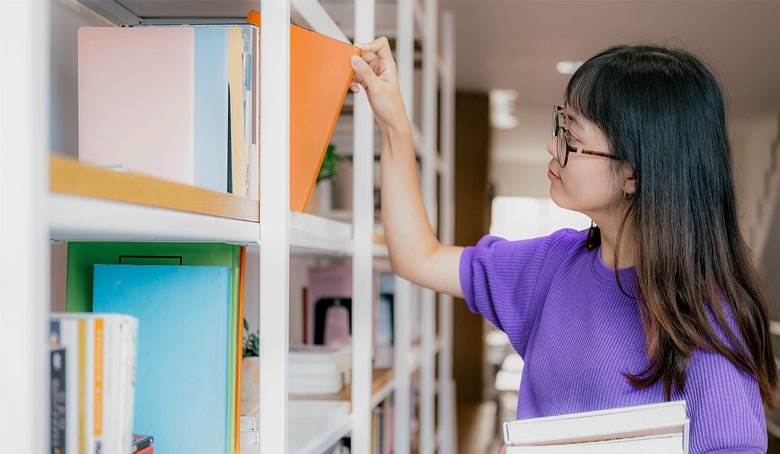 Young adult selecting a book off a shelf