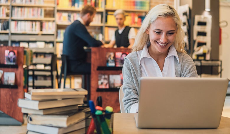Young woman using her laptop at her desk in the library.