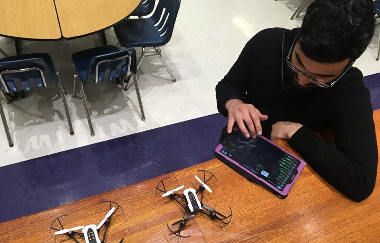 photograph of male student programming a drone in a classroom