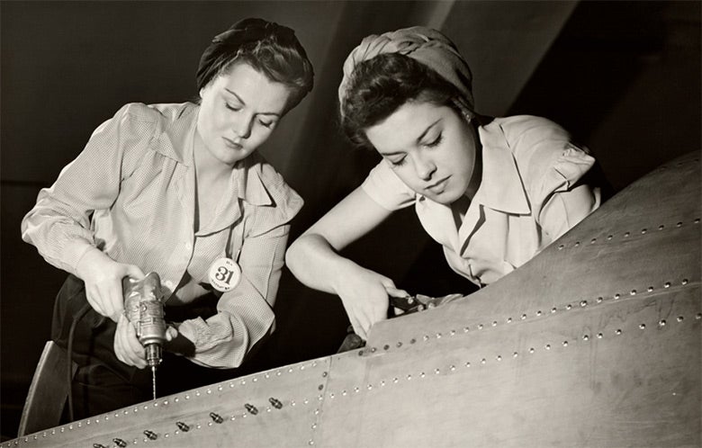 Two women working on an airplane, could be around World War 2.