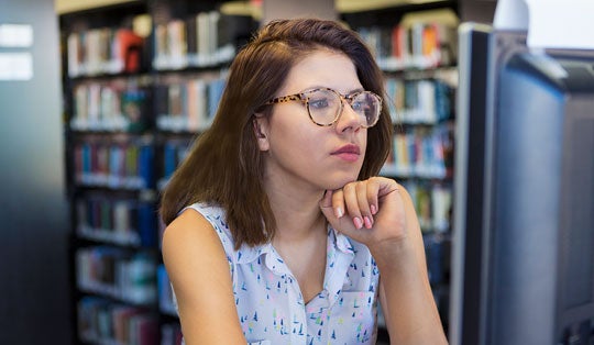 woman sitting at a computer in a library